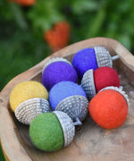 Papoose Toys felt acorns placed in a wooden dish.