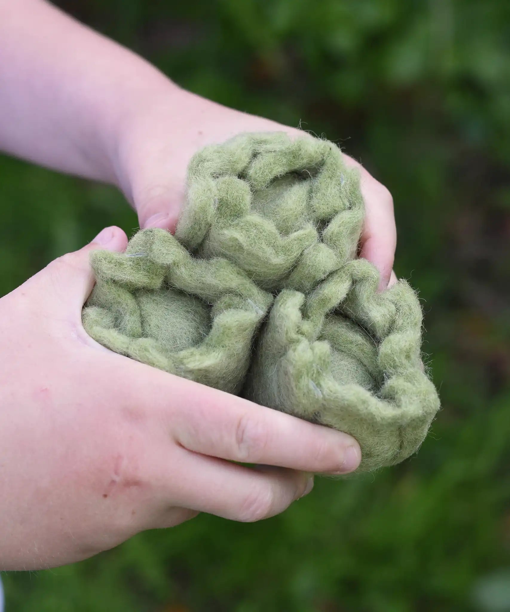 Close up of three Papoose Toys felt cabbage play food in a child's hands.