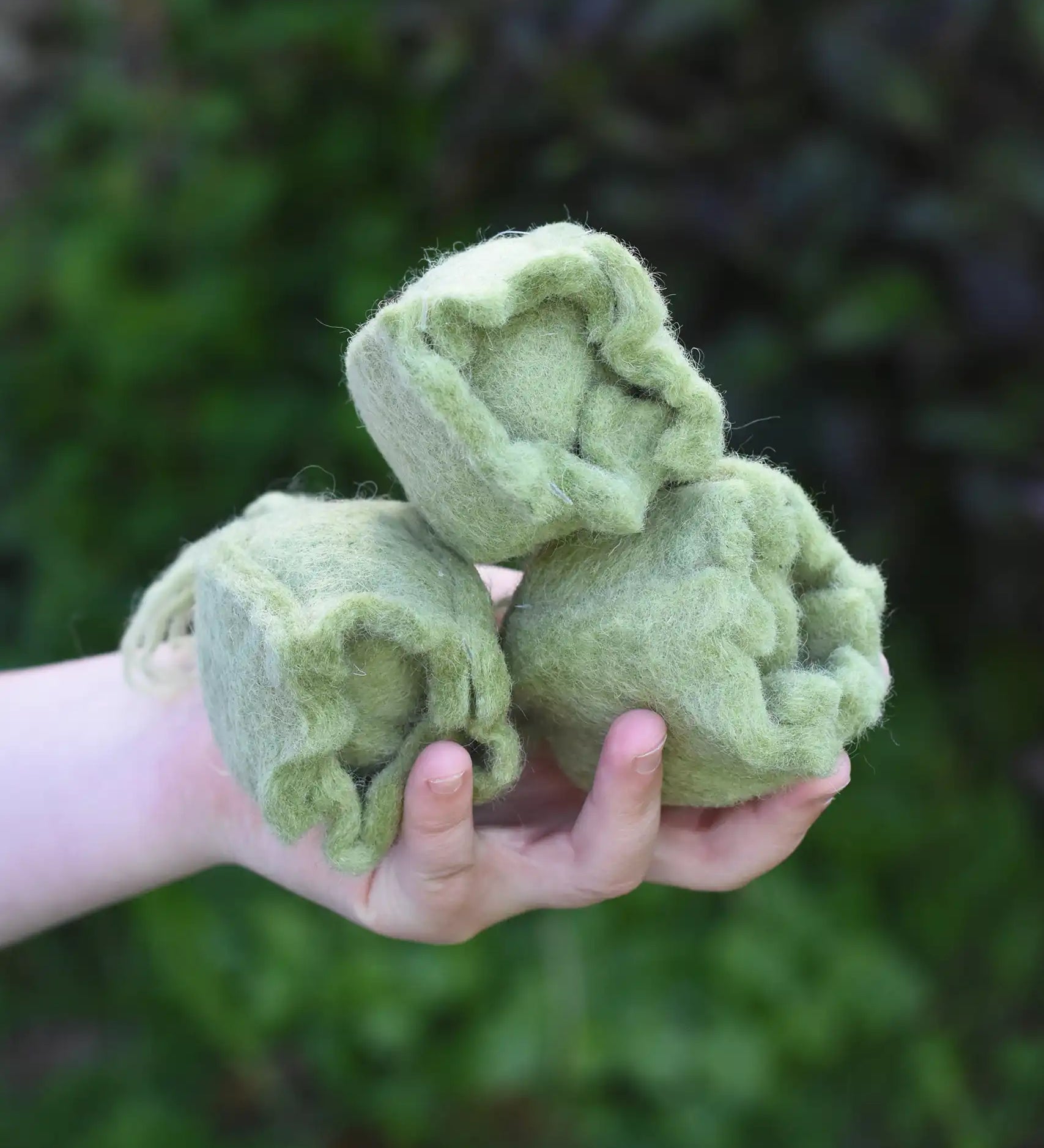 Papoose Toys felt cabbage in a set of three in a child's hands. 