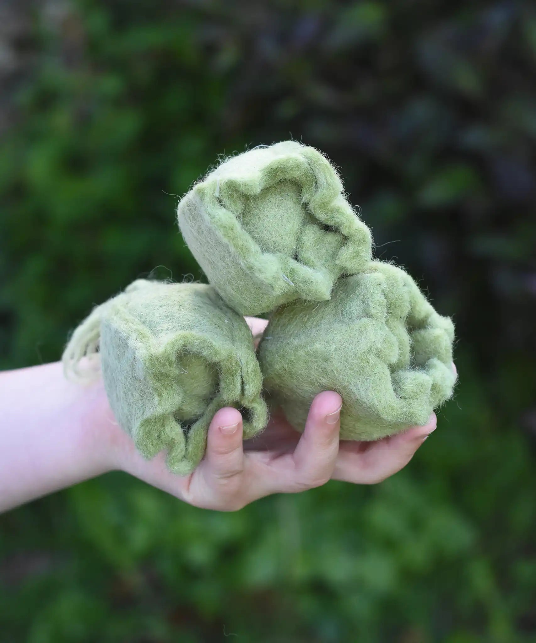 Papoose Toys felt cabbage in a set of three in a child's hands. 