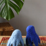 Two blue Papoose felted daffodil flowers placed upside down on a wooden stool to look like little ghosts. 