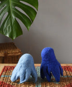 Two blue Papoose felted daffodil flowers placed upside down on a wooden stool to look like little ghosts. 