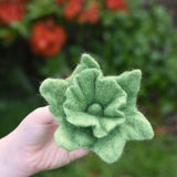 Green Papoose felt Fair Trade rainbow daffodil flower in a child's hand.