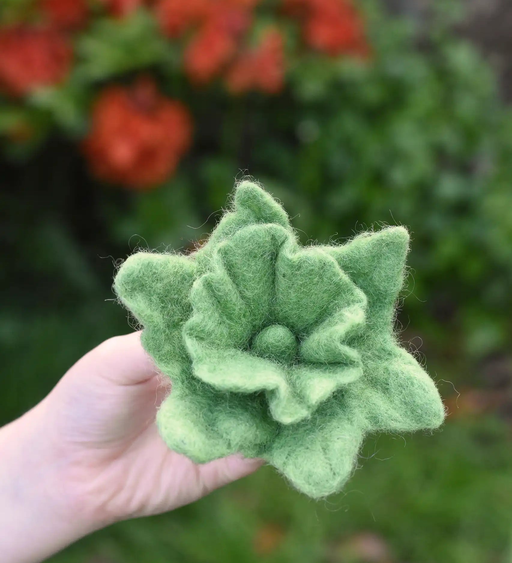Green Papoose felt Fair Trade rainbow daffodil flower in a child's hand.