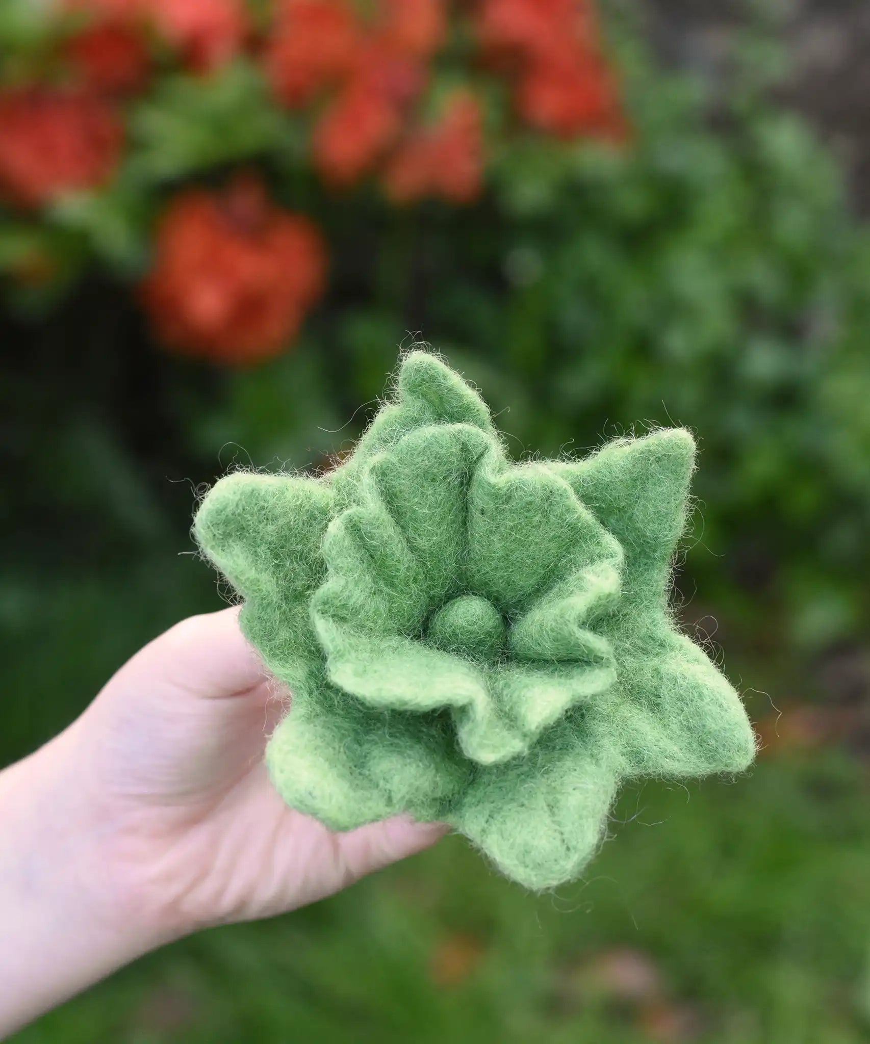 Green Papoose felt Fair Trade rainbow daffodil flower in a child's hand.