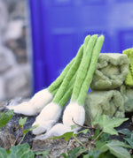 Papoose Toys feltgarlic set in a set of three placed on a stone wall outdoors.