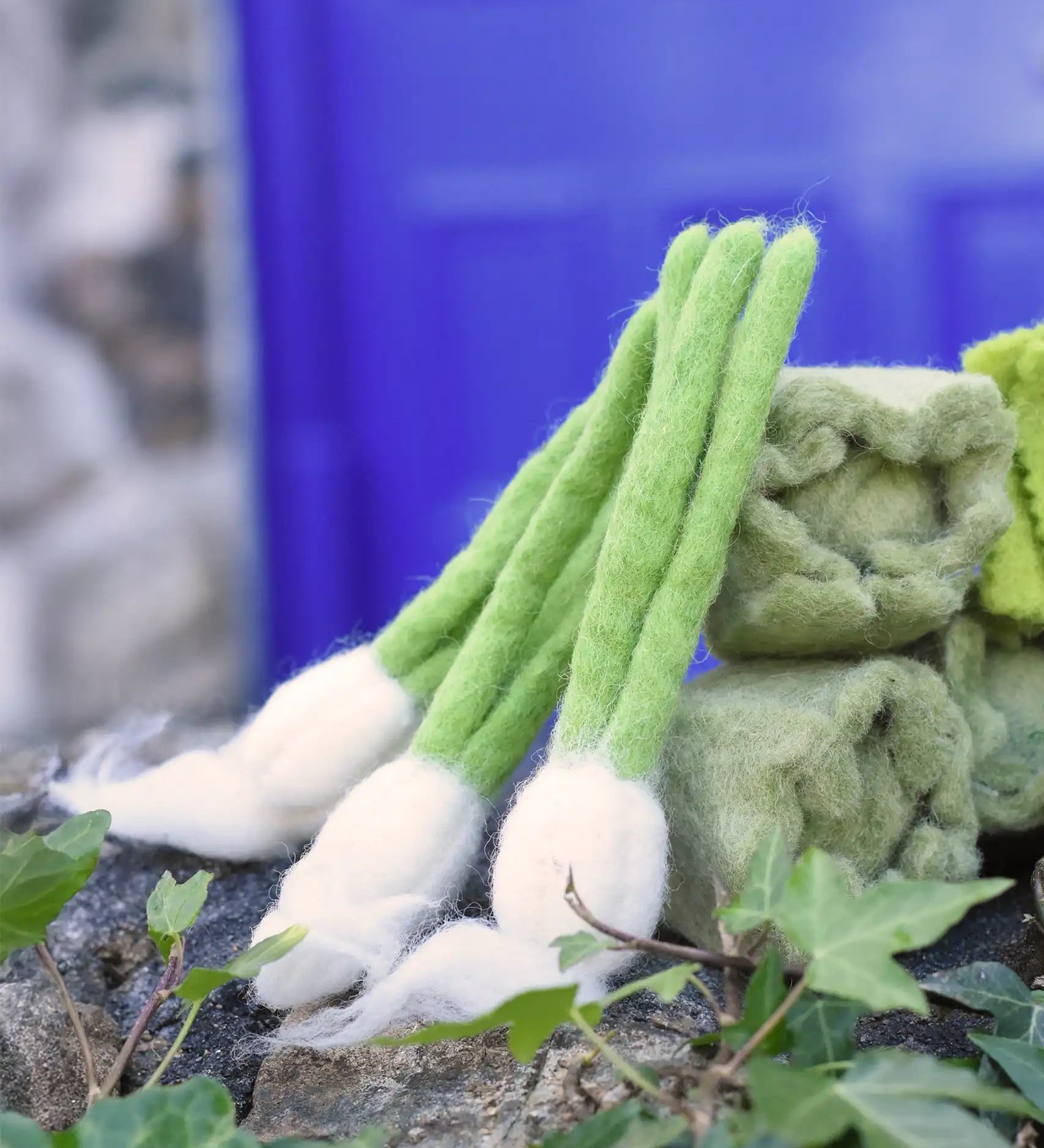 Papoose Toys feltgarlic set in a set of three placed on a stone wall outdoors.