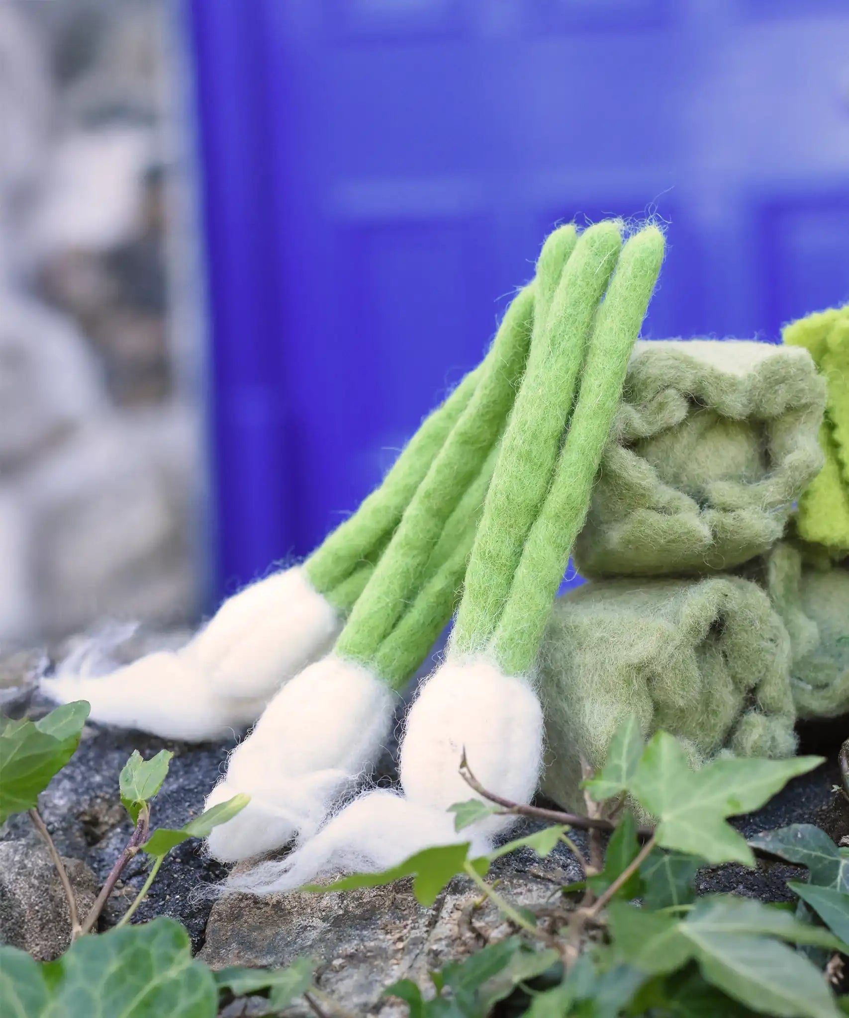 Papoose Toys feltgarlic set in a set of three placed on a stone wall outdoors.
