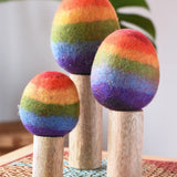 Papoose Toys felt rainbow trees in a set of three placed on a rattan top stool. 