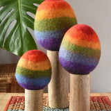 Papoose Toys felt rainbow trees in a set of three placed on a rattan top stool. 