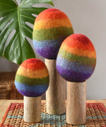 Papoose Toys felt rainbow trees in a set of three placed on a rattan top stool. 