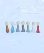 The Papoose Toys Wooden Earth colours People peg dolls placed on a snow covered surface outoors.
