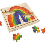 Pieces of the Papoose plastic-free wooden rainbow jigsaw scattered around the wooden base on a white background