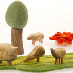 Close up of the Papoose childrens wooden pebble animal toys on a green play mat in front of a Papoose tree