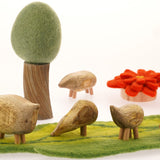 Close up of the Papoose childrens wooden pebble animal toys on a green play mat in front of a Papoose tree
