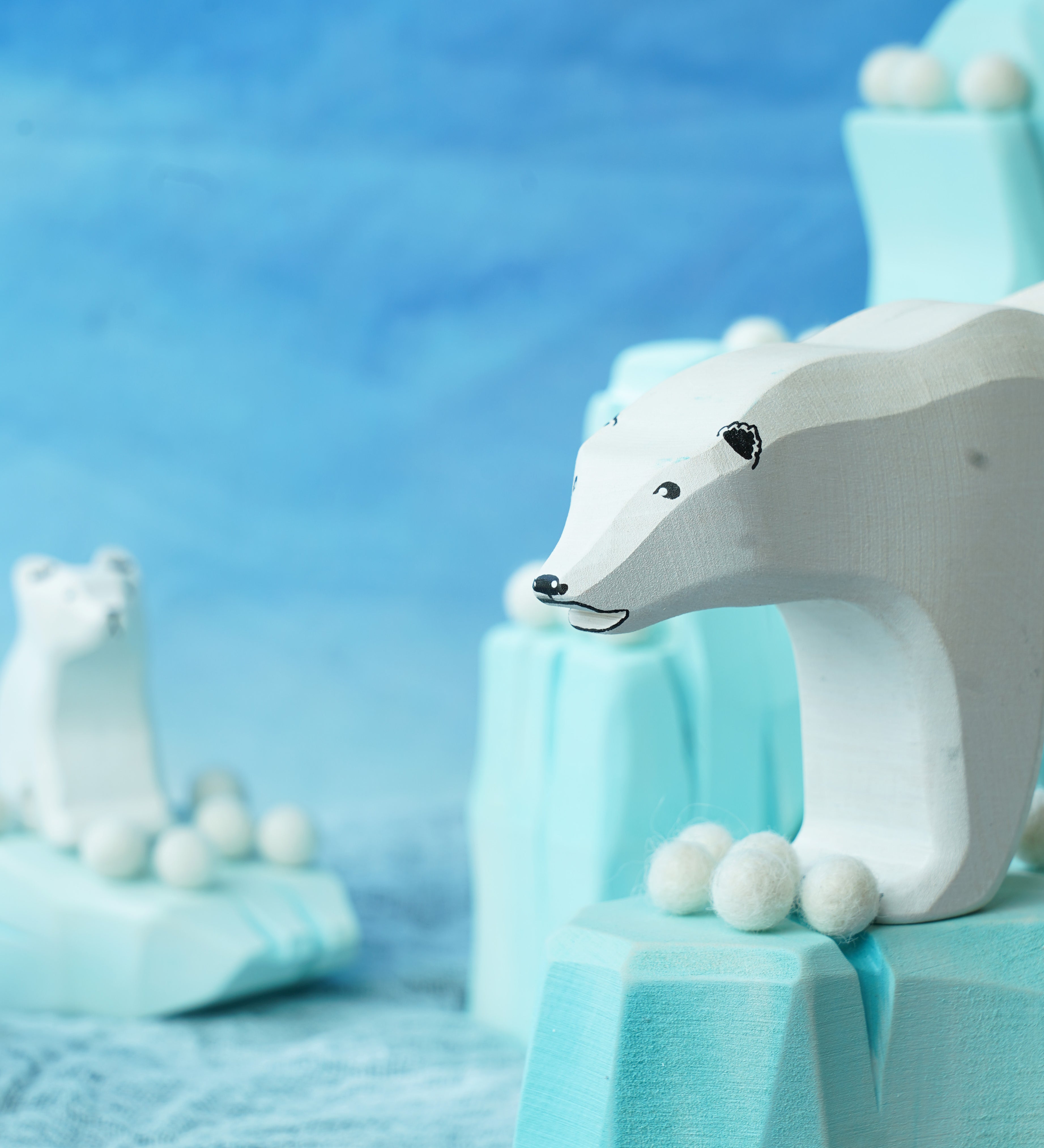 Felted white pom poms on wooden ice rock figures with wooden polar bear figures standing on the ice rocks.