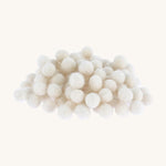 white felted pom poms piled up on a cream backround