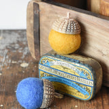 Red and yellow Papoose Toys rainbow acorns on a wooden desk. Felt acorns on hand carved wooden acorn caps.
