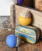 Red and yellow Papoose Toys rainbow acorns on a wooden desk. Felt acorns on hand carved wooden acorn caps.