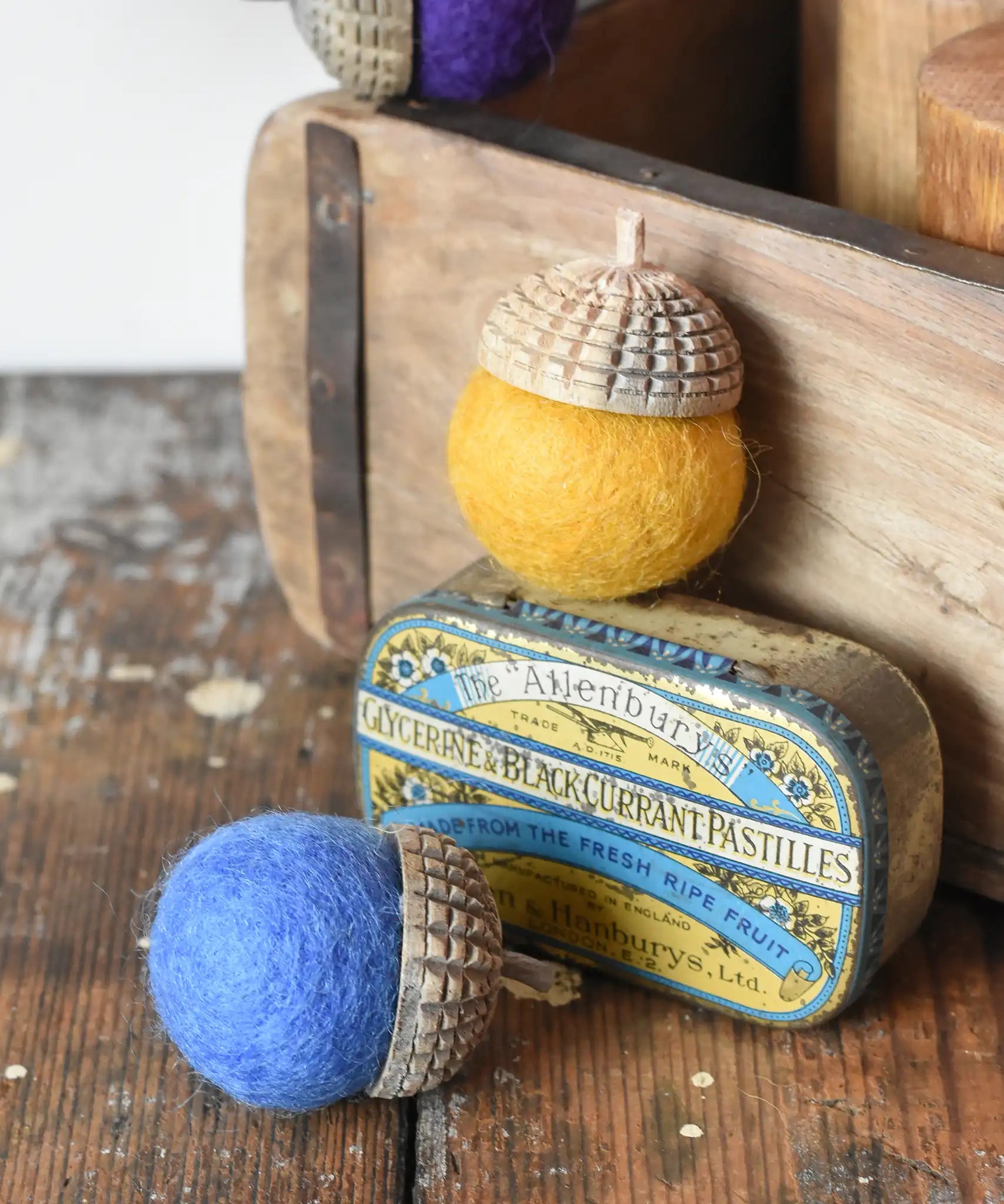 Red and yellow Papoose Toys rainbow acorns on a wooden desk. Felt acorns on hand carved wooden acorn caps.