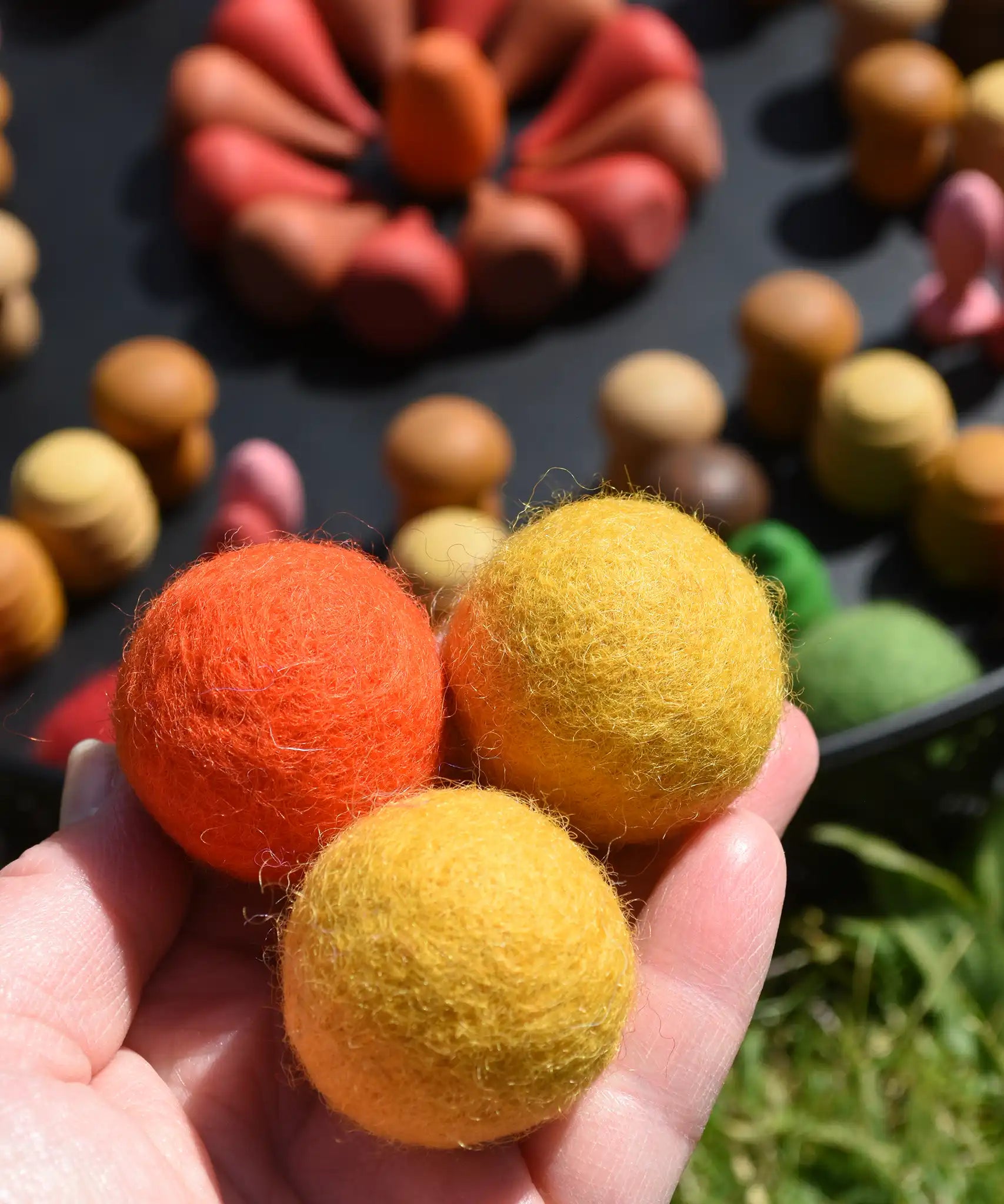 Close up of the Papoose felt balls in an adult's hands.