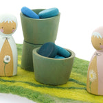 Papoose small wooden earth bowls on a green playmat next to some Peepul wooden figures