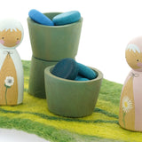 Papoose small wooden earth bowls on a green playmat next to some Peepul wooden figures