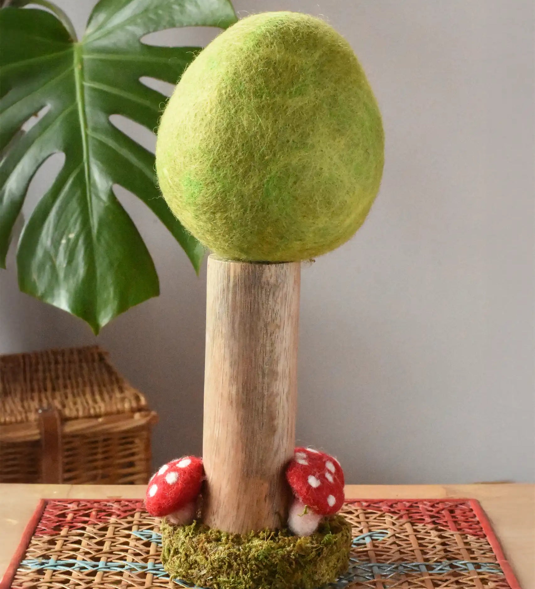 Papoose Toys Spring felt woodland tree placed on a rattan top stool. 