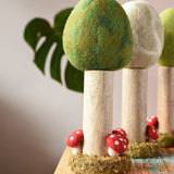 Papoose Toys Summer felt woodland tree placed on a rattan top stool. Winter and Spring versions can be seen in the background. 