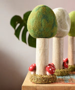 Papoose Toys Summer felt woodland tree placed on a rattan top stool. Winter and Spring versions can be seen in the background. 