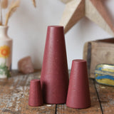 Papoose Toys wooden stacking cones in earth red placed on a wooden desk.
