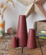 Papoose Toys wooden stacking cones in earth red placed on a wooden desk.