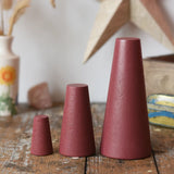 Papoose Toys wooden stacking cones in earth red placed on a wooden desk.
