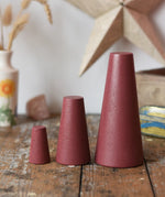 Papoose Toys wooden stacking cones in earth red placed on a wooden desk.
