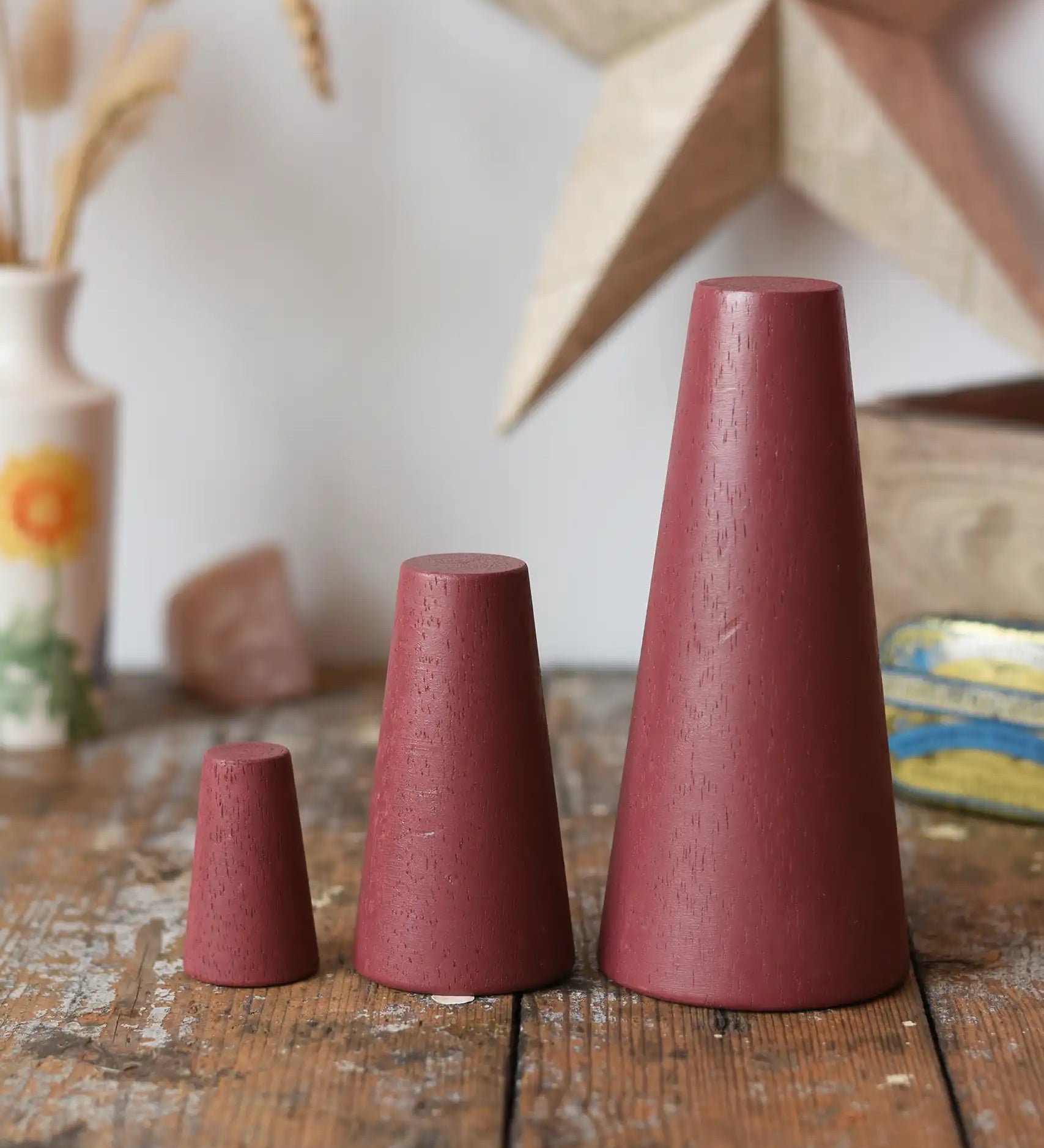 Papoose Toys wooden stacking cones in earth red placed on a wooden desk.
