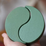 Papoose Toys wooden earth yim yams in green in an adult's hand. 