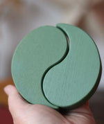 Papoose Toys wooden earth yim yams in green in an adult's hand. 