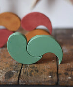 Papoose Toys wooden earth yim yams in green on a wooden desk. 