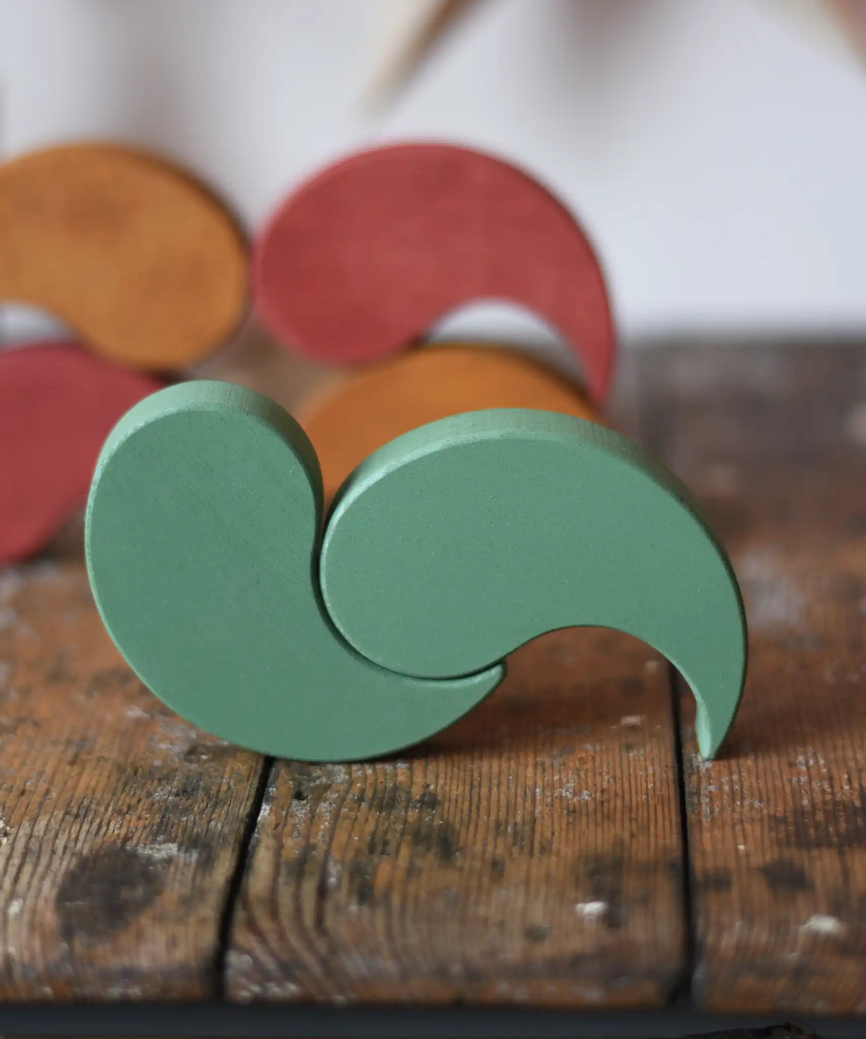 Papoose Toys wooden earth yim yams in green on a wooden desk. 