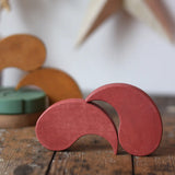 Papoose Toys wooden earth yim yam in red stacked on a wooden desk.