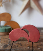 Papoose Toys wooden earth yim yam in red stacked on a wooden desk.
