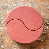 Papoose Toys wooden earth yim yam in red placed on a wooden desk.