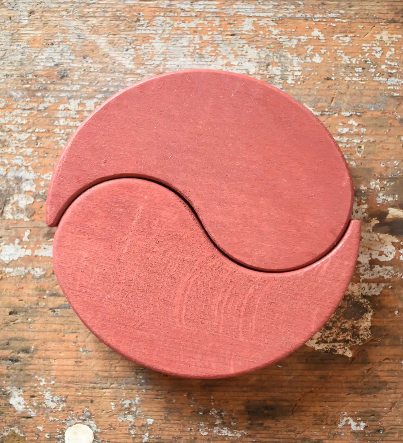Papoose Toys wooden earth yim yam in red placed on a wooden desk.