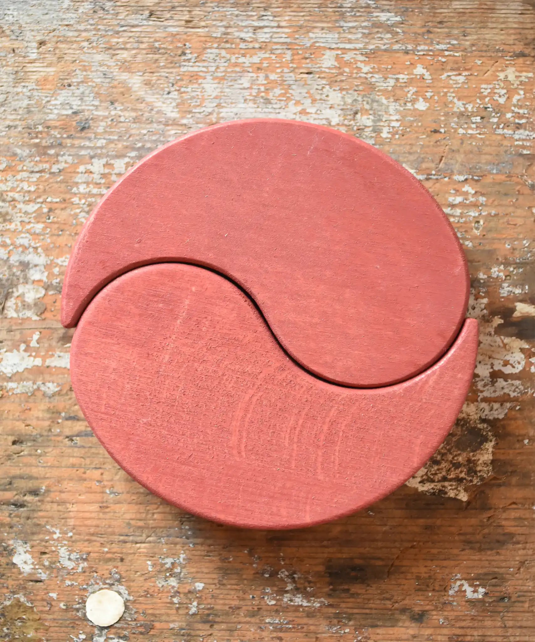 Papoose Toys wooden earth yim yam in red placed on a wooden desk.