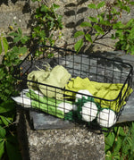 Papoose Toys felt vegetable play food placed in a black wire basket.