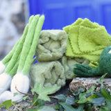 Papoose Toys felt cabbages with other felted veg placed on a stone wall. 