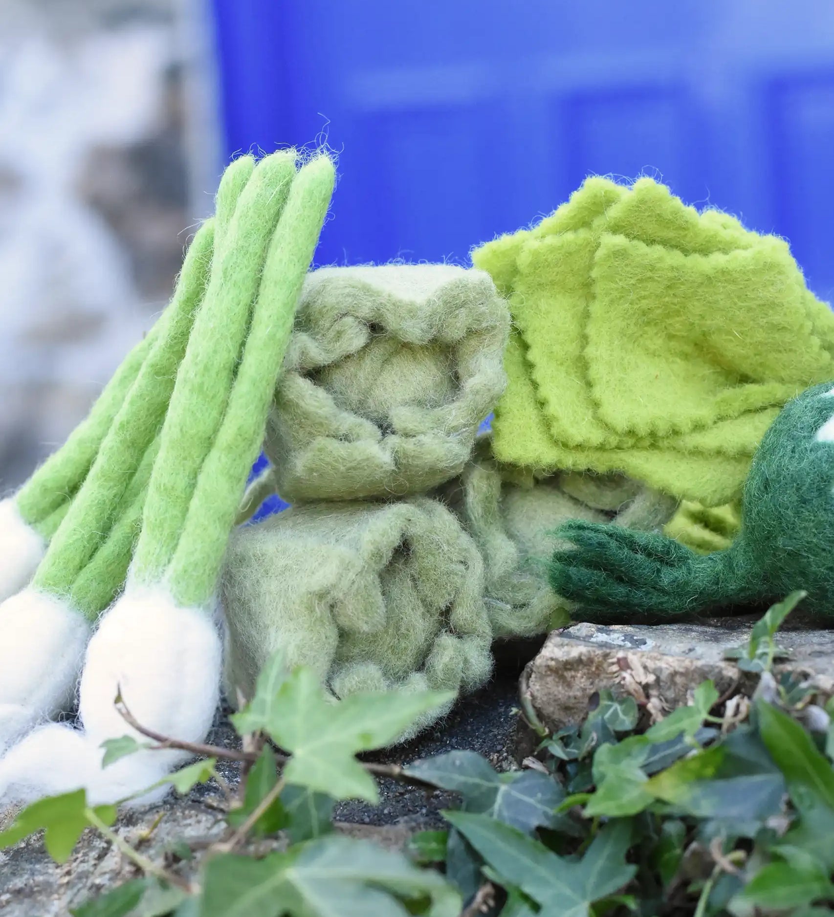 Papoose Toys felt cabbages with other felted veg placed on a stone wall. 