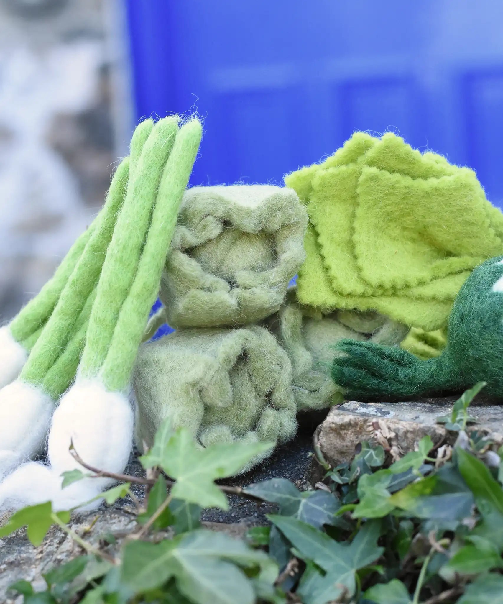 Papoose Toys felt cabbages with other felted veg placed on a stone wall. 
