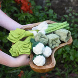 Papoose Toys felt vegetable play food in a wooden dish, held by a child.