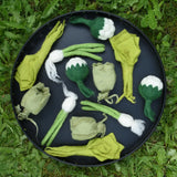 Papoose Toys felt vegetable play food placed on a black tray outdoors.  